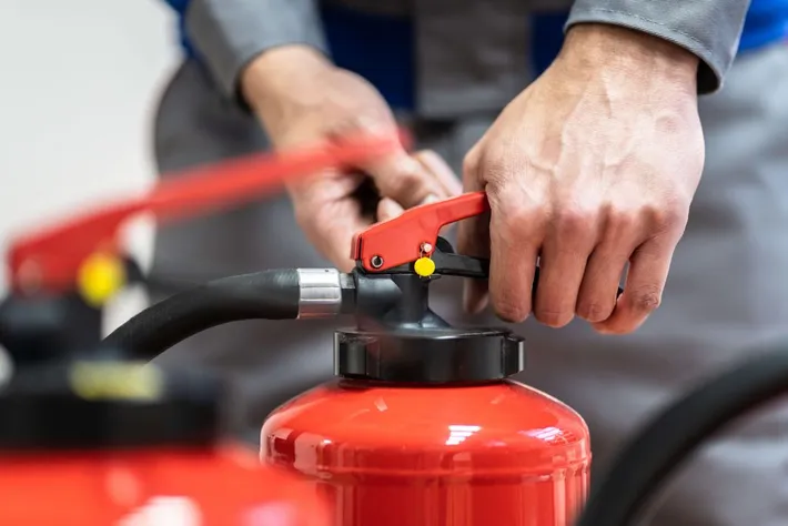 Hand prüft einen roten Feuerlöscher
