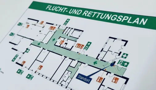 Ausgedruckter Flucht- und Rettungsplan mit Grundriss, markierten Fluchtwegen, Notausgängen und Standort