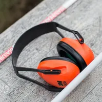 Oranger Kapselgehörschutz liegt auf einem verwitterten Holzbrett