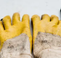 Nahaufnahme eines Paars abgenutzter gelber Arbeitshandschuhe mit Beschichtung