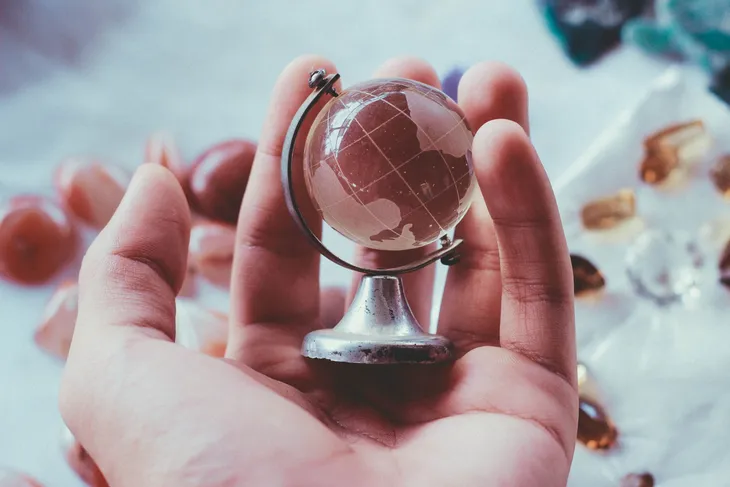 Hand hält einen kleinen Glasglobus als Symbol für mehrsprachige Unterweisungen in internationalen Teams