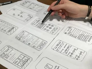 Hand skizziert mit Stift Wireframes von Smartphone-Ansichten auf Papierbögen