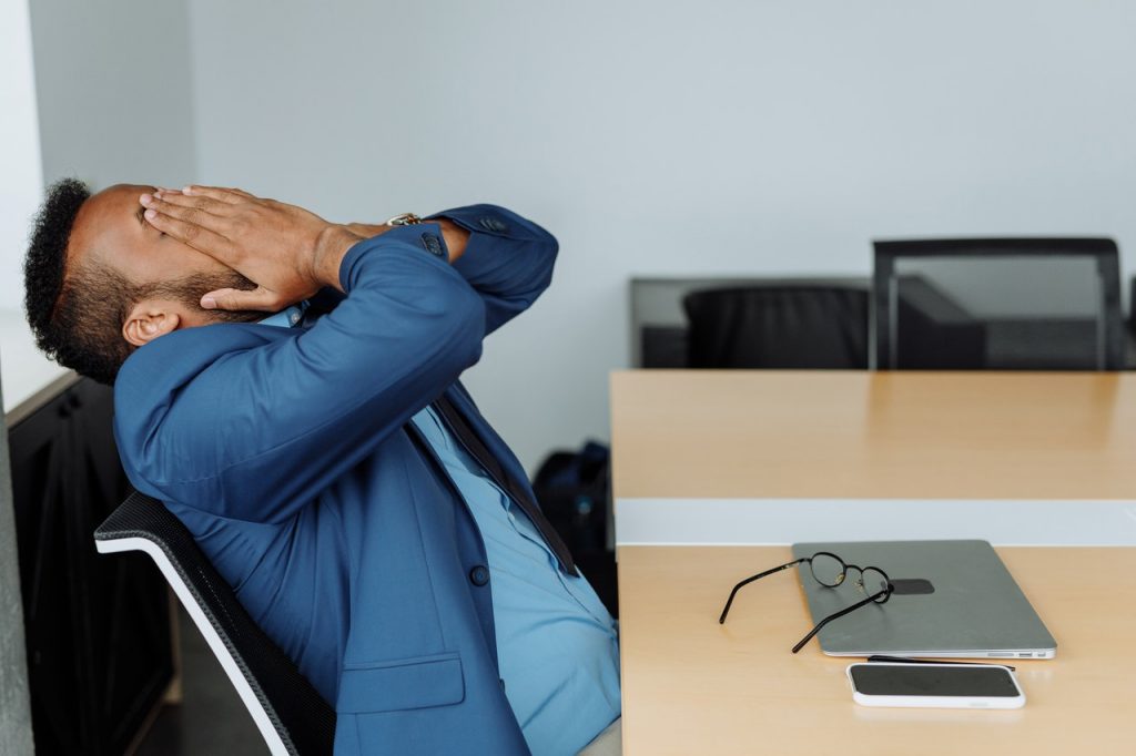 Gesundheit am Arbeitsplatz: Mann, welcher aufgrund von Stress seine Hände vor seinen Kopf hält